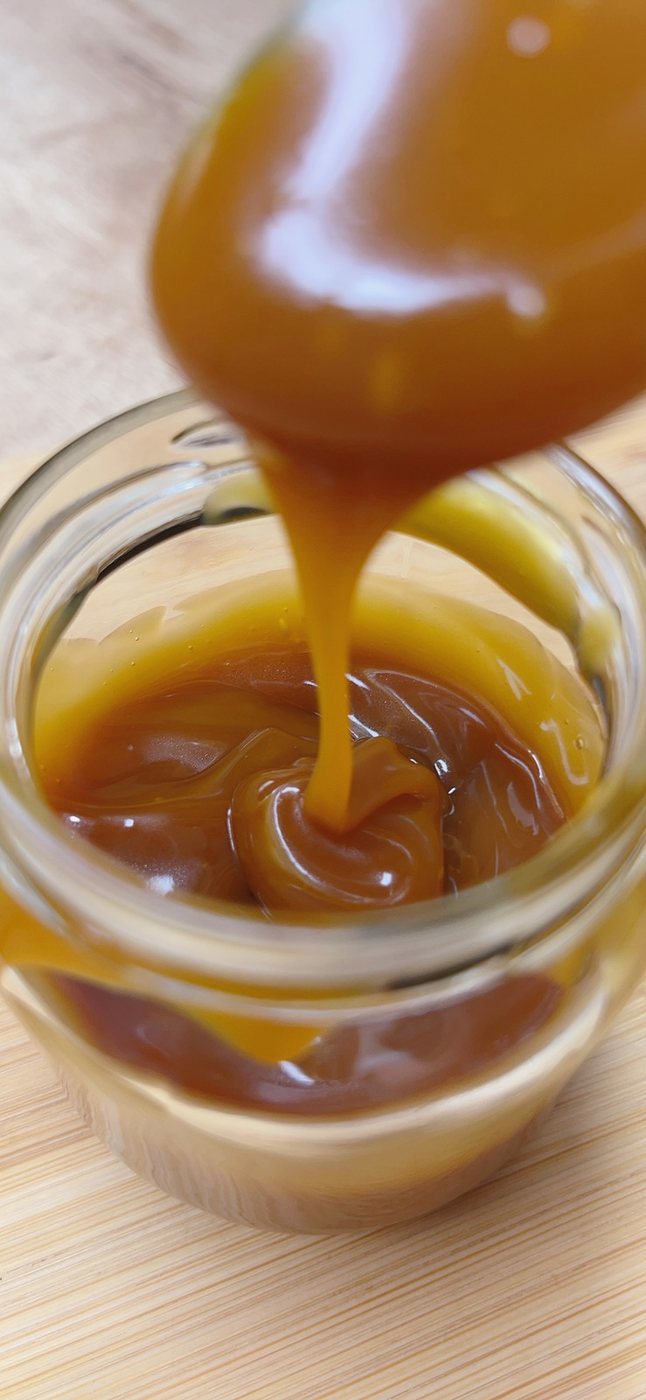 Salsa de arequipe sin azúcar keto cayendo dentro de un frasco de vidrio